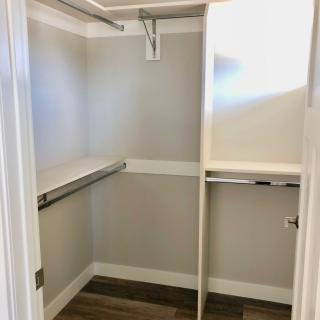 An empty walk-in closet with hanging rods and shelves.
