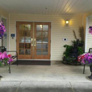 A welcoming entrance with double wooden doors, flanked by benches and potted flowers.