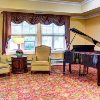 A cozy living room setting with a grand piano and comfortable chairs.
