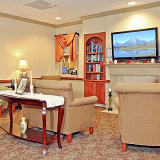 A cozy living room with comfortable seating, a mounted television, and a bookshelf for decor.