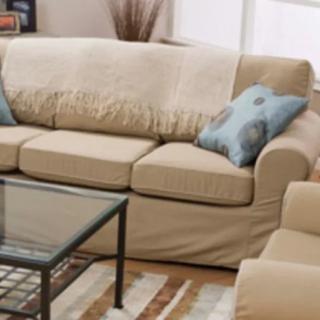 A cozy living room featuring a beige sofa with blue pillows, complemented by a glass coffee table and a patterned rug.