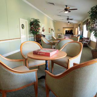 A spacious lounge area with comfortable chairs and a central table, surrounded by plants.