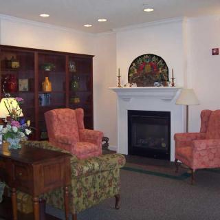 A cozy living room with a fireplace, armchairs, and a bookshelf.