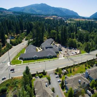 Aerial view of a rural area with buildings, surrounded by forests and mountains.