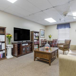 A cozy living room with a large television, bookshelves, and a coffee table.