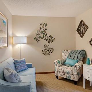 A cozy living room with a sofa, patterned armchair, and decorative wall art.
