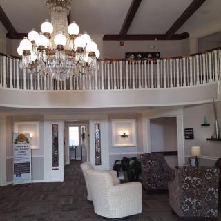 Elegant lobby with a large chandelier, seating area, and balcony.