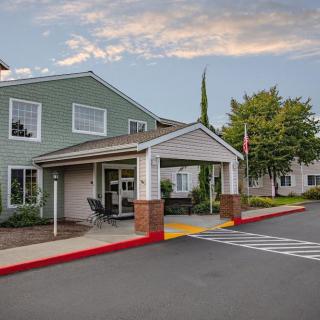 An entrance to a residential building with surrounding trees and a clear sky.