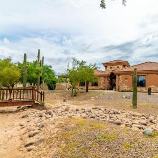 A desert home with cacti and a rocky landscape in the foreground.