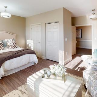 A bright and cozy bedroom featuring a double bed with decorative pillows, neutral color scheme, and ample natural light.