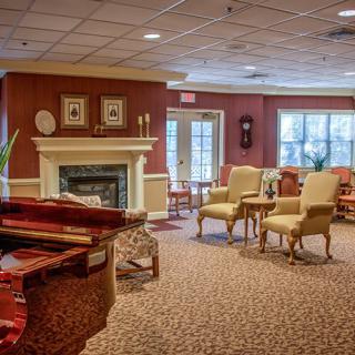 A cozy living room with a piano, fireplace, and comfortable seating.