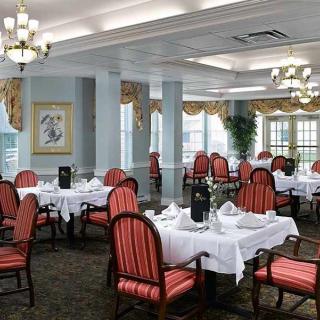 An elegant restaurant dining room with neatly arranged tables and chairs, adorned with chandeliers.