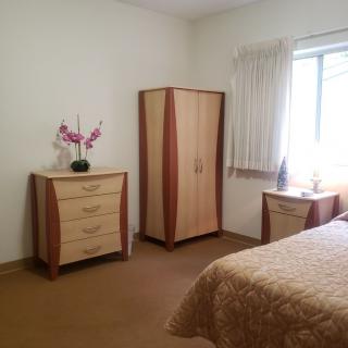 A tidy bedroom with matching furniture and floral decor.