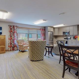 A spacious open-concept living area featuring a kitchen, dining table, and comfortable seating with large windows and bright lighting.