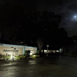 A quiet street scene illuminated by moonlight on a rainy night.
