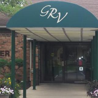 Entrance with a green awning labeled 'GRV' leading to glass doors.