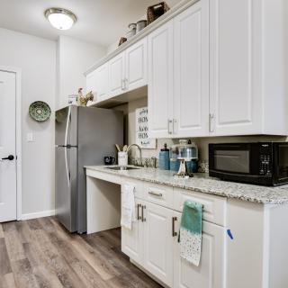 A modern kitchen with white cabinets, a stainless steel refrigerator, and a microwave.