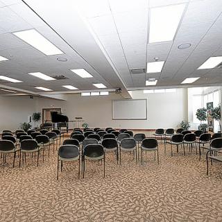 An empty conference room with arranged chairs and a projector screen.