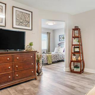 A cozy bedroom with a dresser, TV, and a ladder shelf leading into an adjacent space.