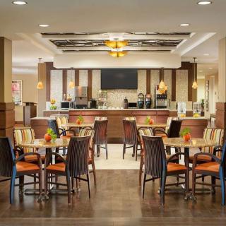 A modern dining area with tables and chairs, featuring a bar in the background.