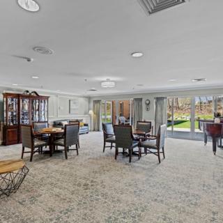 A spacious dining area with multiple tables and chairs, featuring large windows that allow natural light to fill the room.