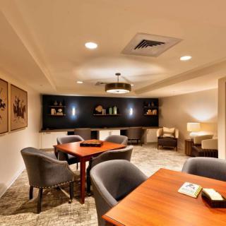 A cozy lounge area featuring modern furniture and warm lighting with tables and upholstered chairs.