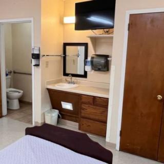 A hotel room featuring a sink, television, and access to a bathroom.