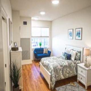 A modern and cozy bedroom with a large bed, stylish decor, and a blue loveseat.