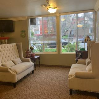 A cozy living room with two white sofas facing each other, a large window providing natural light, and warm decor.