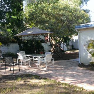 A peaceful outdoor patio with seating and an umbrella surrounded by greenery.
