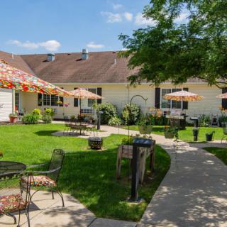 A well-maintained garden with patio seating, umbrellas, and a scenic pathway.