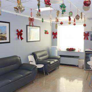 A decorated waiting room with holiday-themed embellishments, featuring grey sofas and bright natural light.