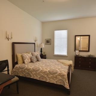 A cozy bedroom with a neatly made bed, decorative pillows, and warm lighting.