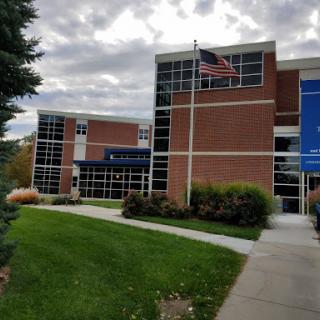 An educational building with modern architecture, featuring large windows and an American flag.