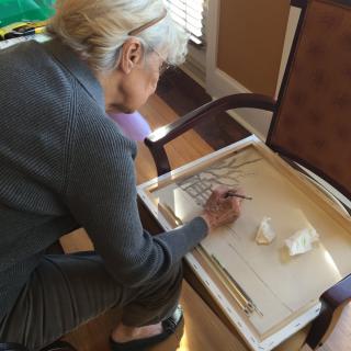 A woman engaged in painting on a canvas indoors.