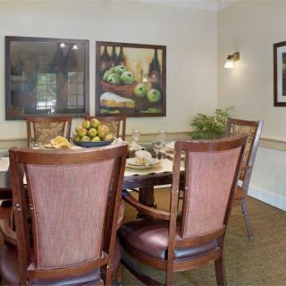 A cozy dining area with a wooden table, surrounded by elegant chairs and decorated with artwork on the walls.