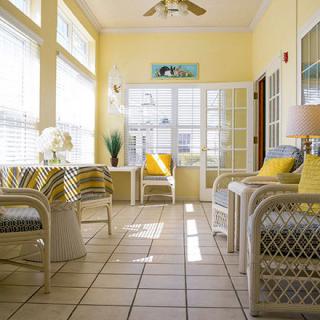 A bright and cozy sunroom with wicker furniture and abundant natural light streaming through large windows.