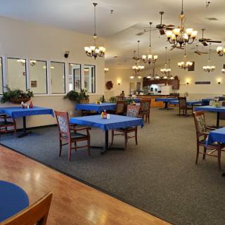 A spacious and elegantly decorated dining area with blue tablecloths and charming chandeliers.