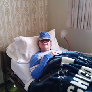A person resting in a hospital bed covered with a blanket.