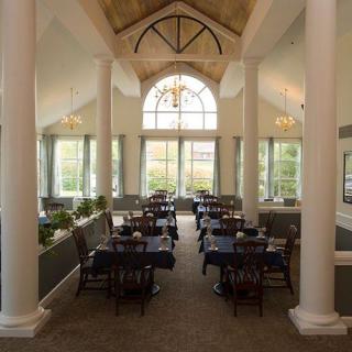 A spacious dining area with elegant columns, large windows, and well-arranged tables and chairs.