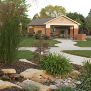 A beautifully landscaped garden with a winding pathway leading to a cozy brick house.