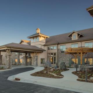 A modern building with a stone exterior and landscaped driveway under a clear sky.