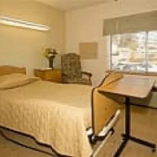 A hospital room with a single bed, a side table, and a window.
