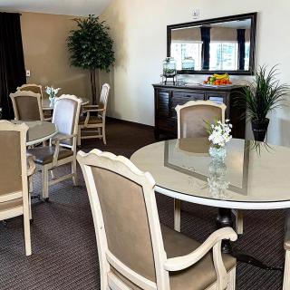 A well-decorated dining area with round tables, cushioned chairs, and indoor plants.