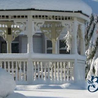 A snow-covered gazebo surrounded by a serene winter landscape.