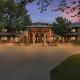 A beautifully lit building entrance surrounded by trees at dusk.