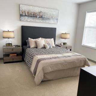 A modern bedroom with a neatly made bed, bedside tables, and decorative lamps.