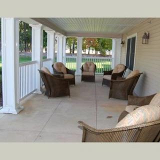 A cozy and inviting porch with wicker chairs arranged for relaxation.
