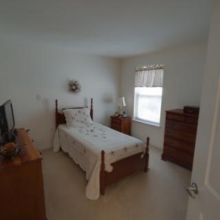 A cozy bedroom with a single bed, dresser, and a window allowing natural light.