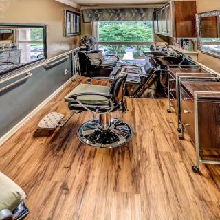 Interior view of a barber shop with wooden floors and styling chairs.